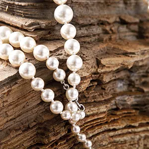 collier de perles naturelles blanches posé sur un morceaux brut de liège