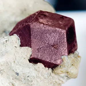 Gros plan sur un cristal géométrique rouge sombre de grenat