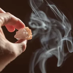 Main tenant une pierre de protection pour la purifier en la passant à travers la fumée d'encens