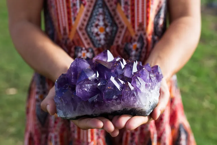 Jeune femme tenant dans ses mains un bel amas de cristaux d'améthyste