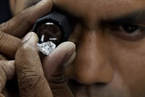 Bijoutier observant un diamant brut à la loupe