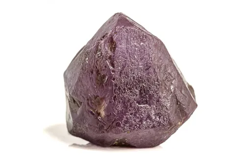 Pierre alexandrite rouge violette sur fond blanc à la lumière du jour