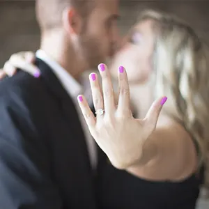 jeune femme embrassant son compagnon et montrant la bague avec des diamants
