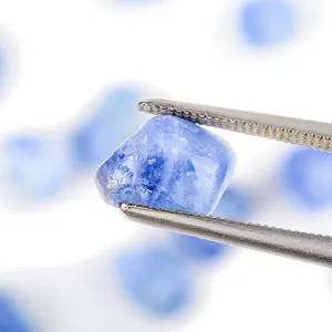 Pierre saphir bleue, à l'état brut, tenue par des pinces de joaillier